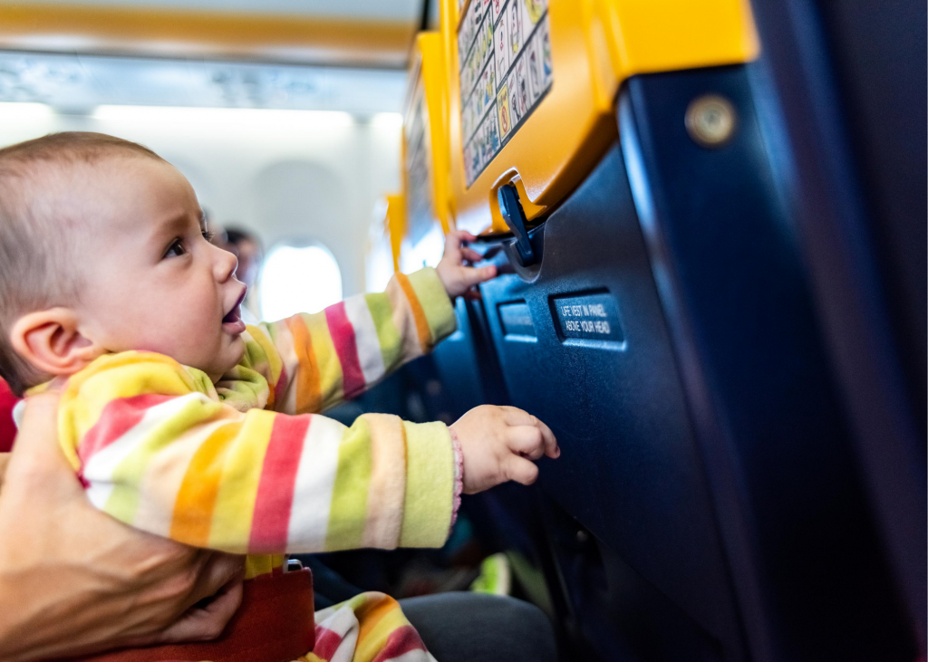 Baby on a plane playing with the seat back