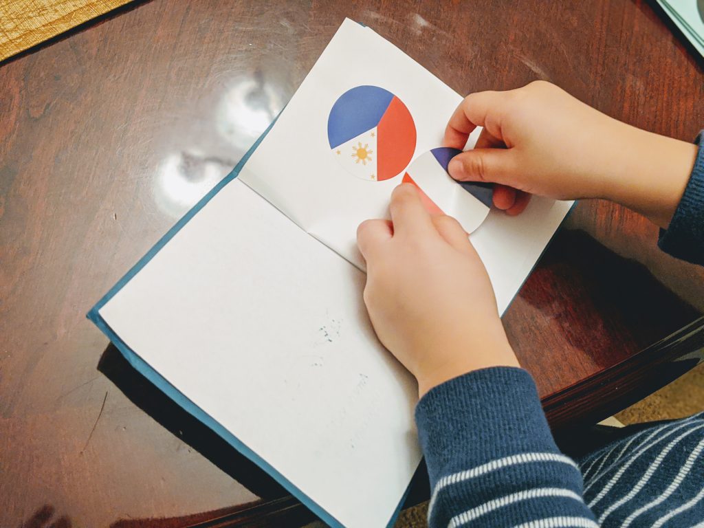 Putting a French flag in the passport at the end of the France preschool unit