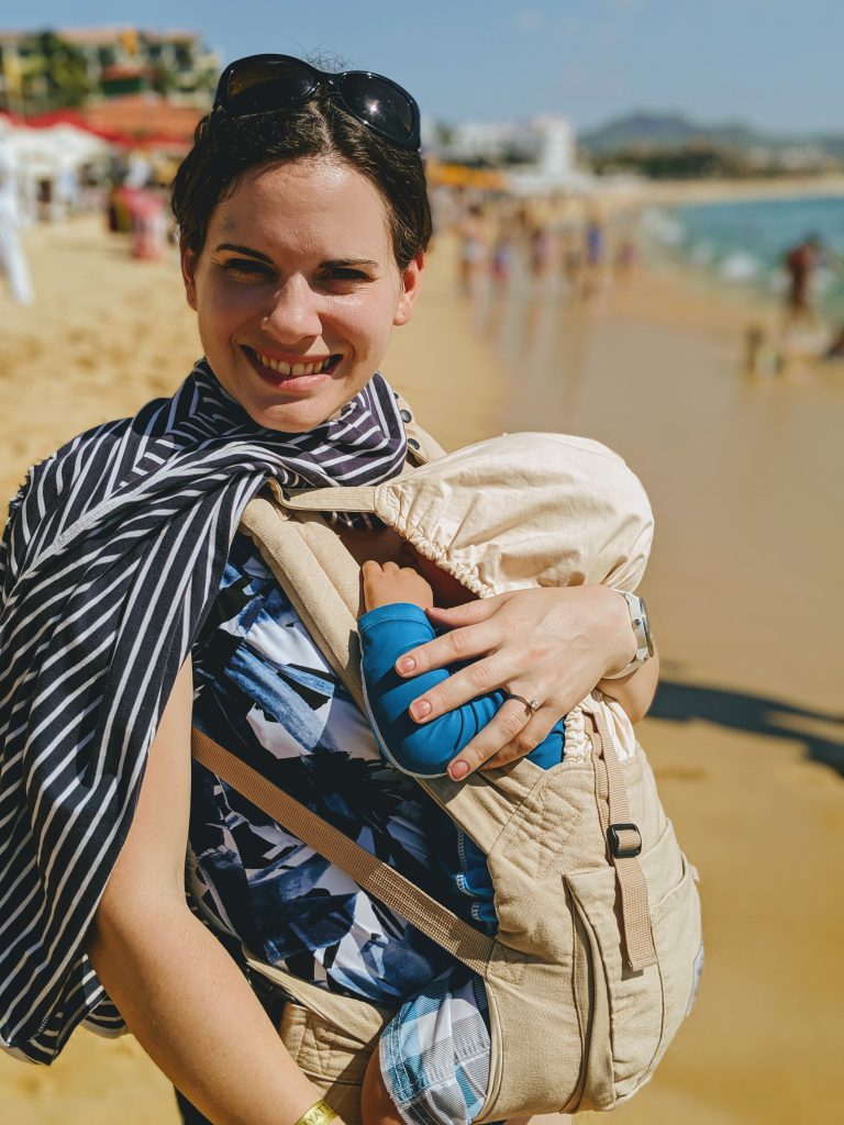 Baby taking a nap in a baby carrier on the beach