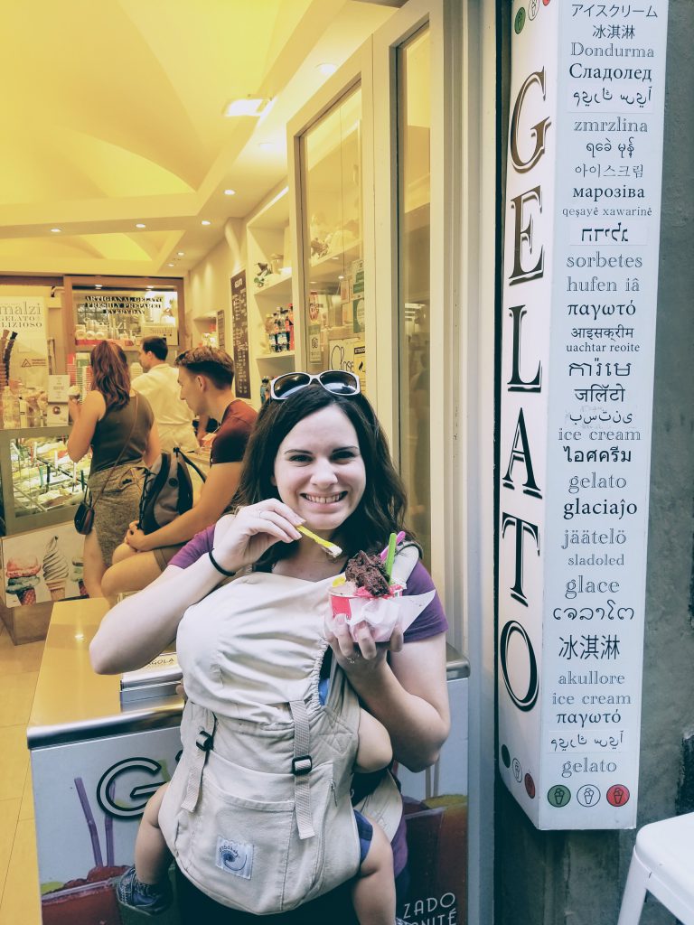 Mom wearing baby in a baby carrier while eating gelato with her hands free