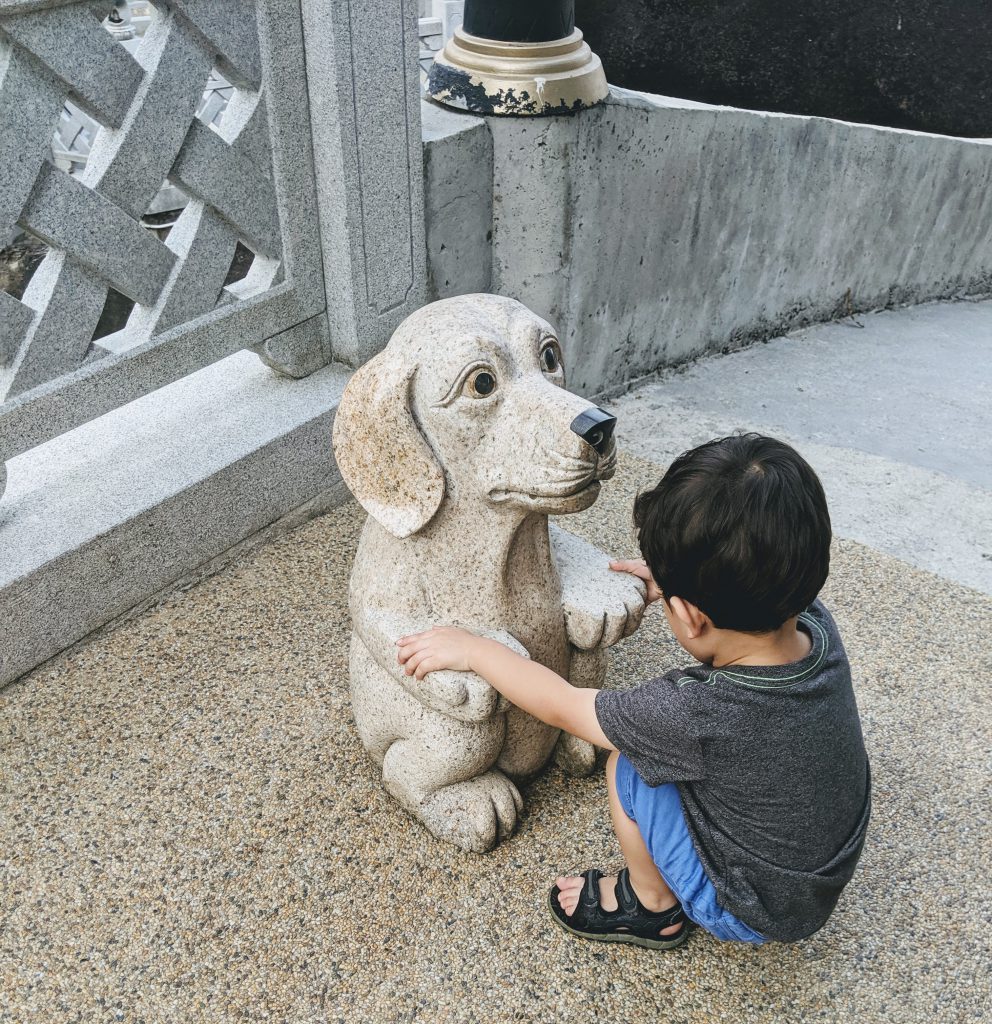 A boy with a dog statue at Kek Lok Si Temple in Penang, Malaysia