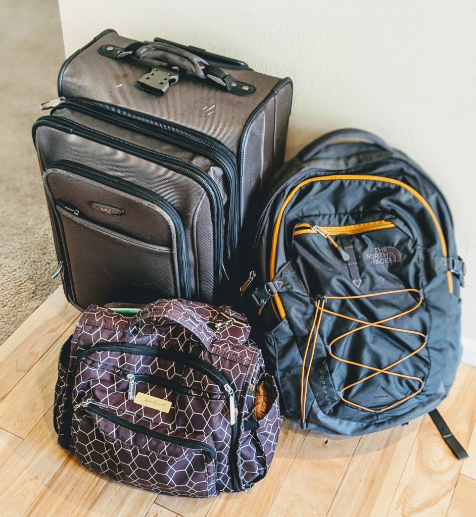 A suitcase and two backpacks for packing light on a trip to Italy with a baby