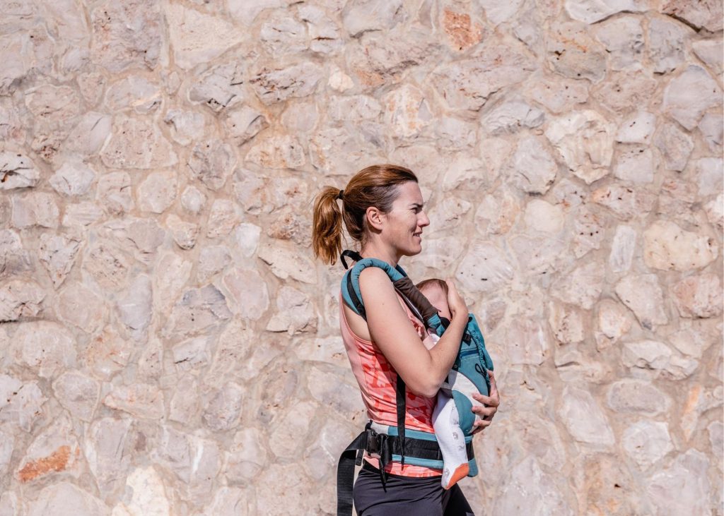 Woman walking with a baby in a baby carrier