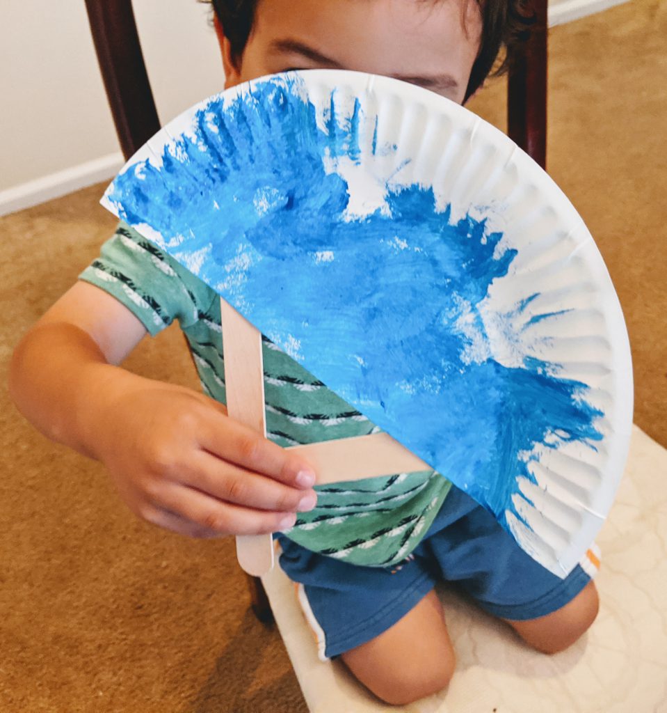 Boy holding the fan he made for the Japanese preschool unit