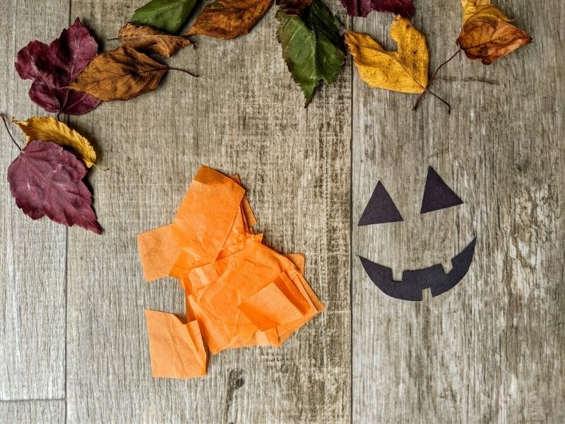 Cut out orange tissue paper and a pumpkin face for the jack-o'-lantern from black construction paper