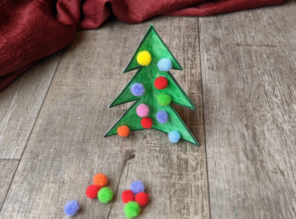 Add pom poms to complete the Christams tree craft