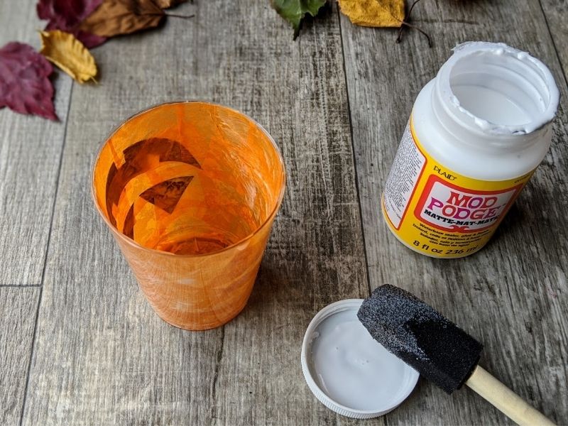 Jack-o'-lantern cup craft completely covered in tissue paper on the inside