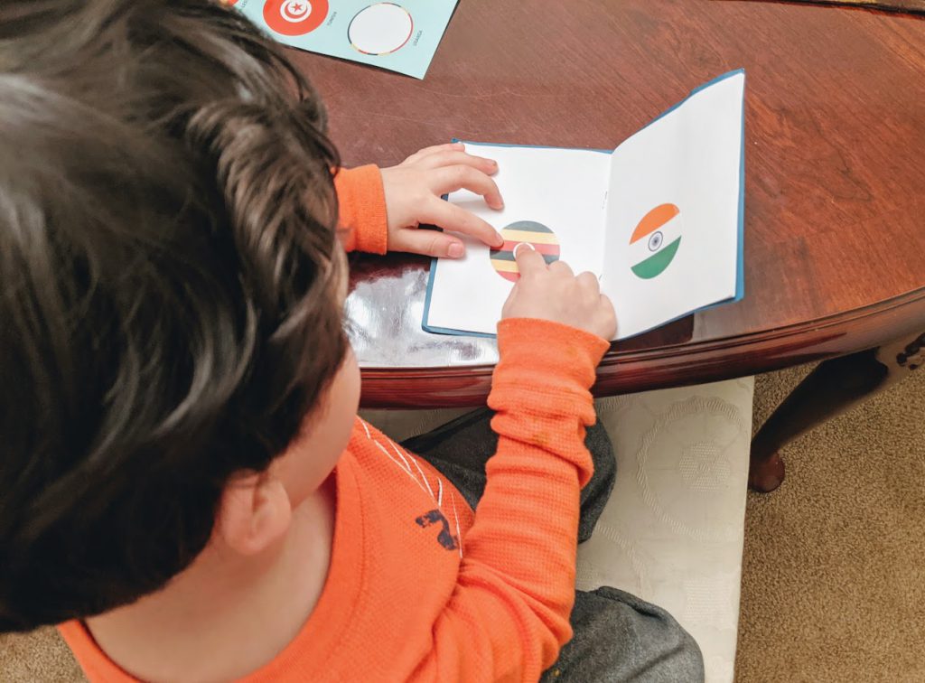 Putting the Uganda flag sticker in his pretend passport