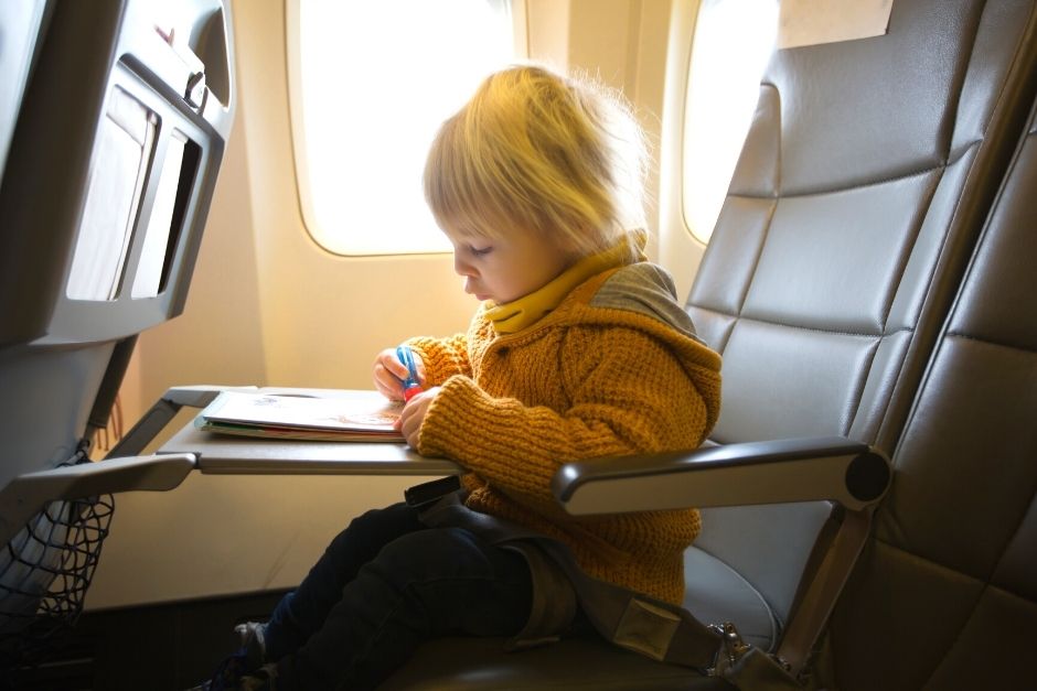 Toddler on an airplane drawing in a book