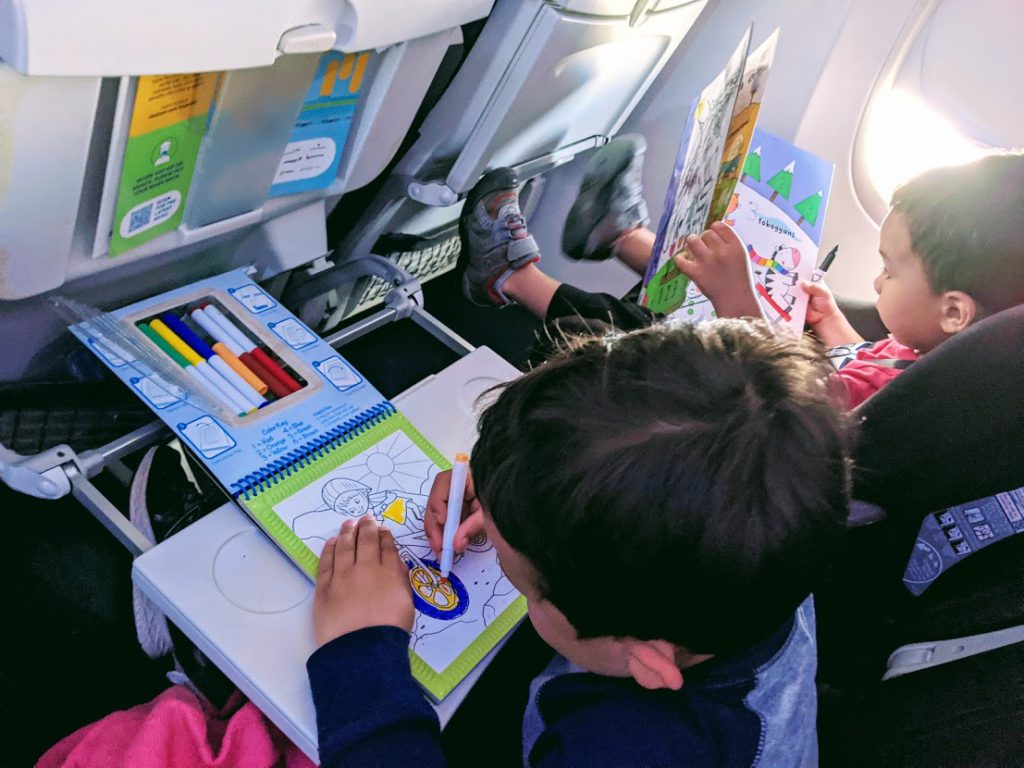 Two children drawing in books on a plane- how to entertain a toddler on a plane