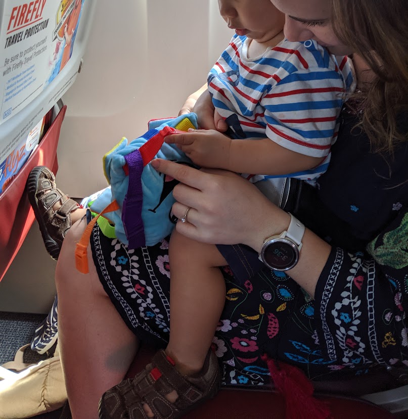 Child playing with a buckle toy on a plane