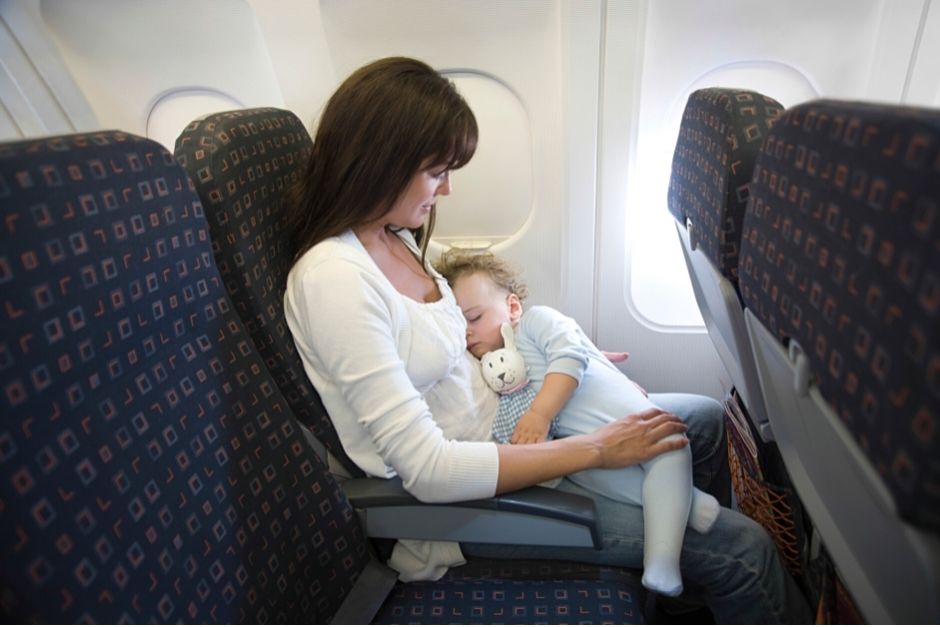 Woman holding a sleeping baby on the plane- first flight with baby