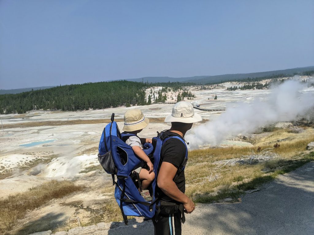 A man with a toddler in a carrier looking out over Porcelain Basin