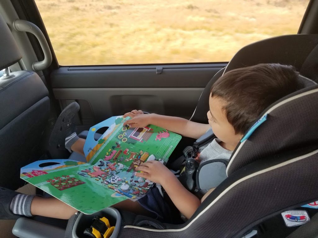 Child  playing with a puffy sticker book- toddler airplane activities