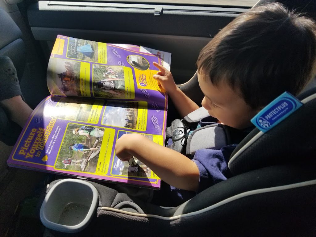 Child reading a book in the car- toddler road trip activities