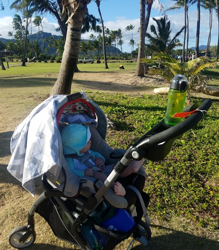 Baby next to the beach in a car seat frame stroller