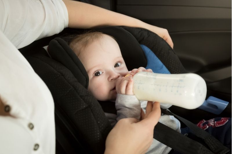 Baby with bottle in car- road tripping with a baby