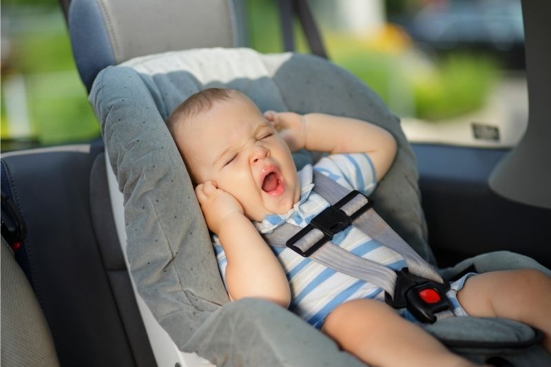 Baby yawning in a car seat- road tripping with a baby