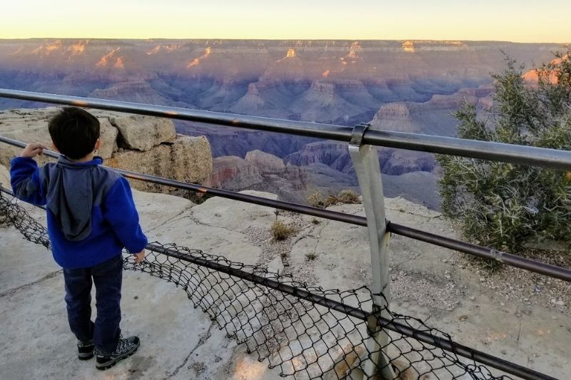Boy looking at the Grand Canyon from behind a railing