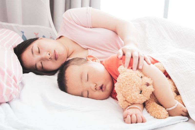 Mother and toddler sleeping in a bed