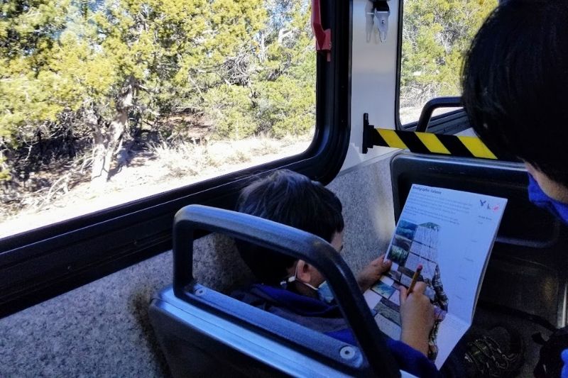 Boy working on his junior ranger book on a bus