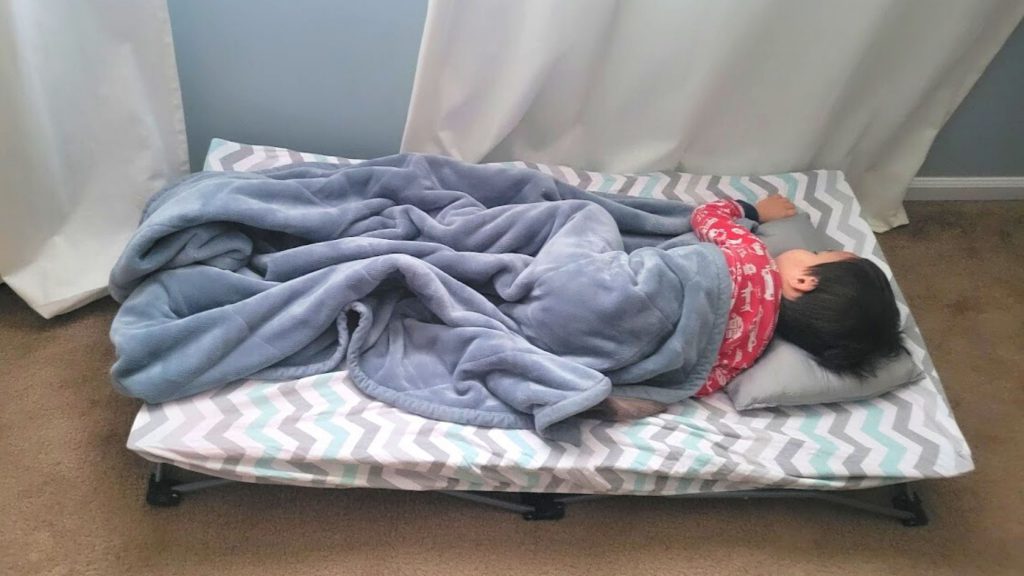 Child sleeping on a portable toddler cot