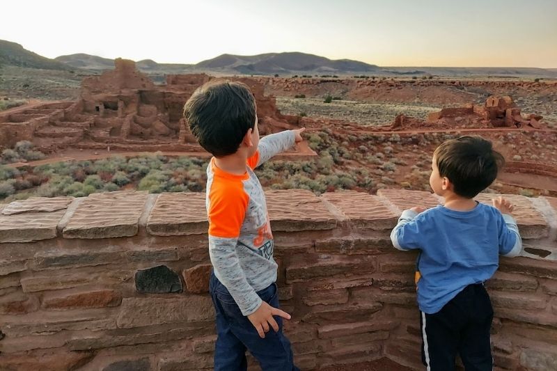 Two kids looking out over Wupatki ruins