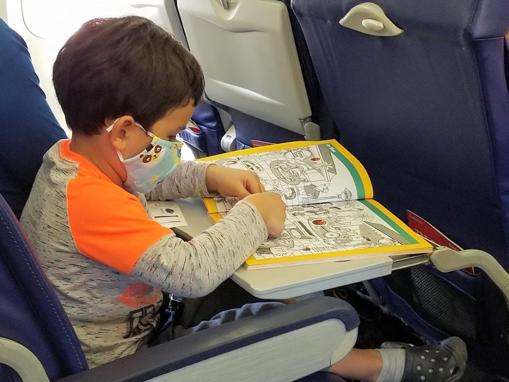Child working on a hidden pictures book on a plane