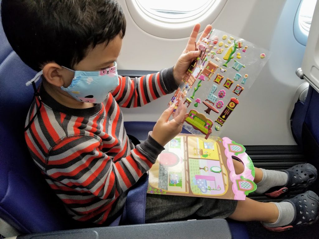 Child working on a puffy sticker set on a plane