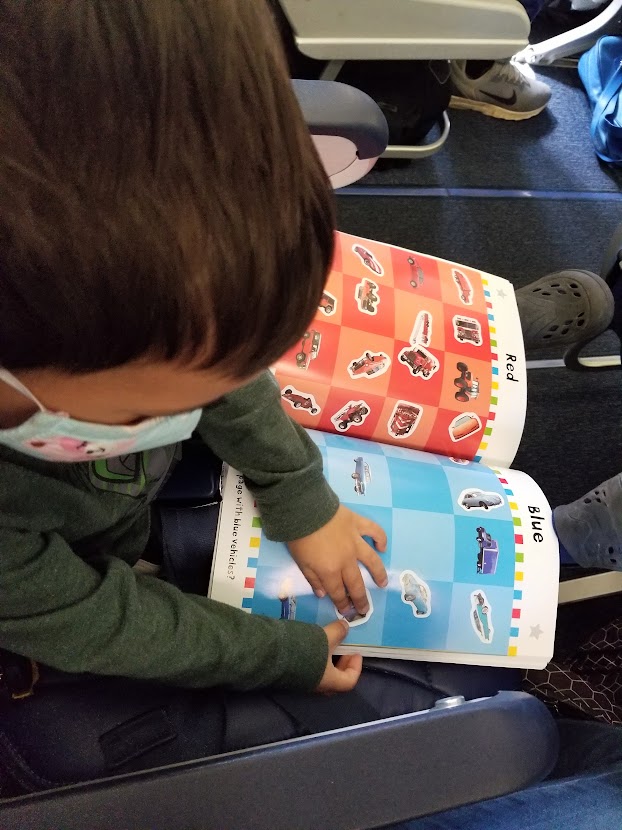 Child working on a sticker book on a plane