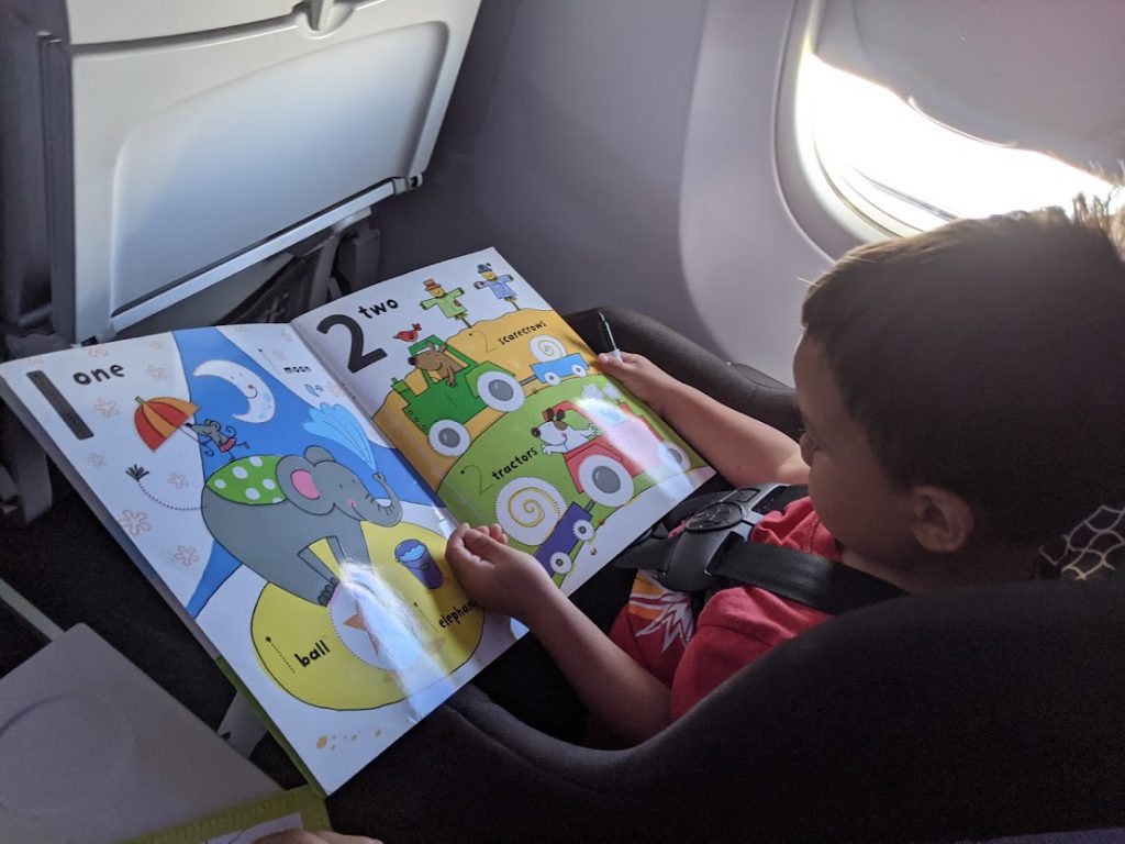 Child looking at an Usborne Wipe Clean book on a plane