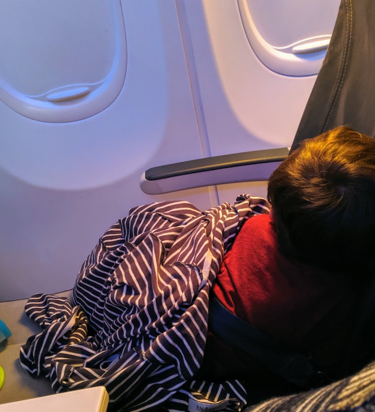 Child sleeping on an airplane using an inflatable footrest