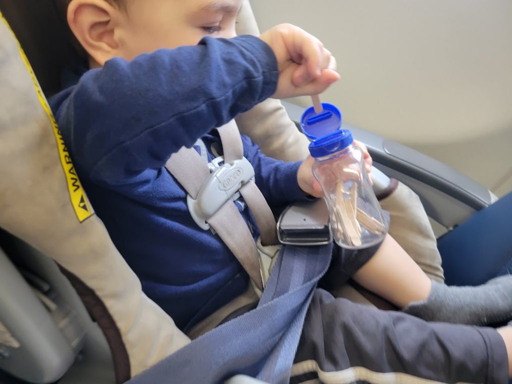 Child playing with a stick jar on a plane