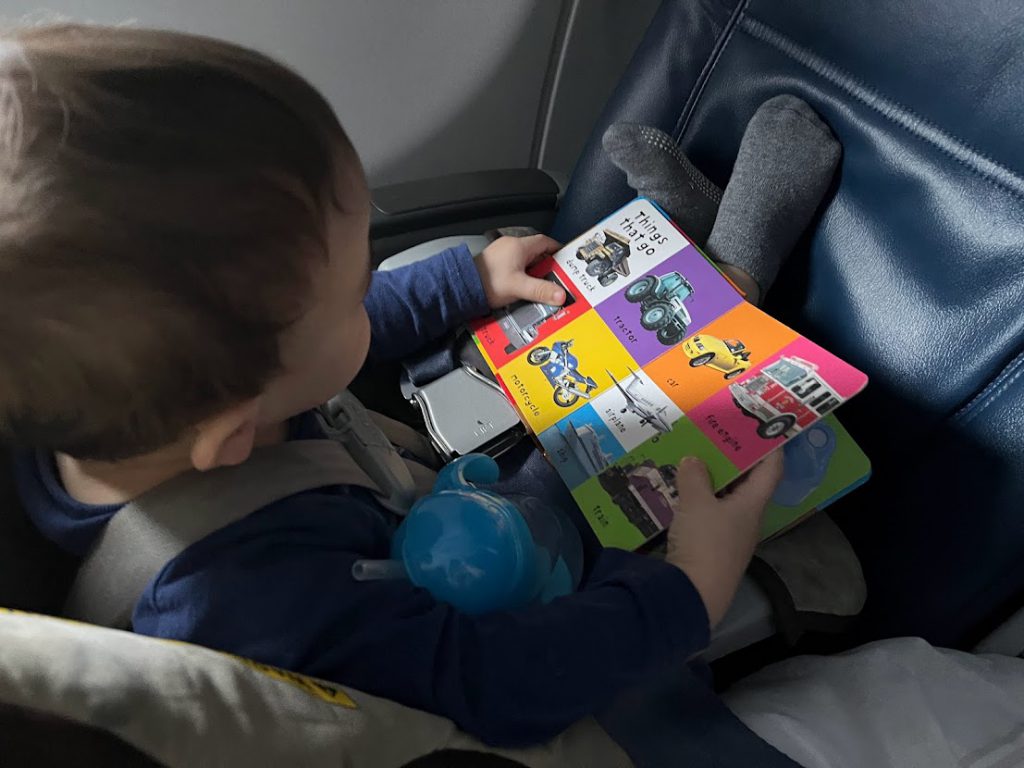 Toddler reading a book on a plane