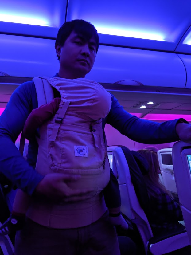 Toddler asleep in a baby carrier on an airplane