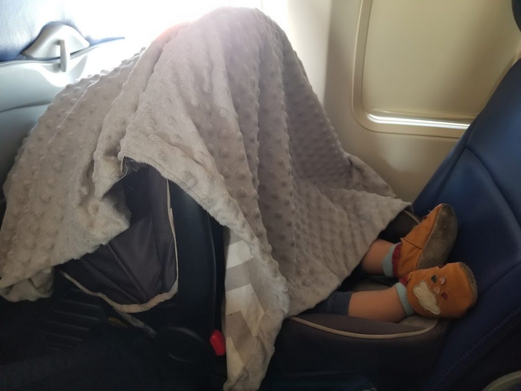 Toddler in car seat sleeping on a plane