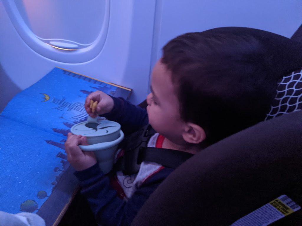 Child eating a snack and reading a book on a plane