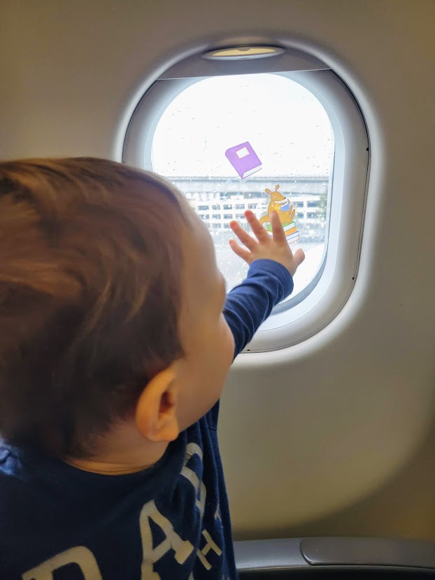 Toddler playing with window clings on plane