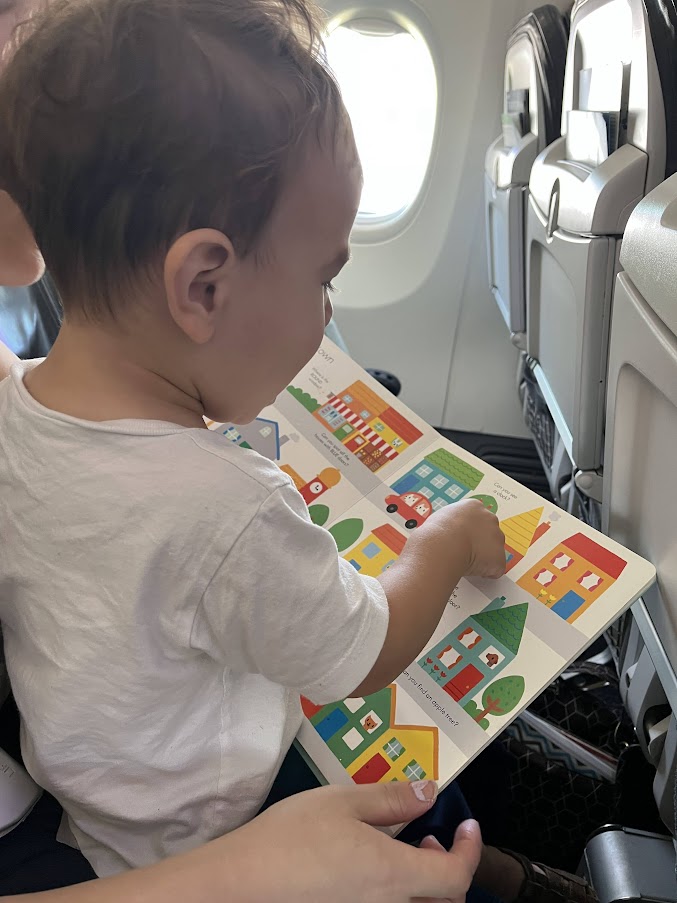 Toddler reading book on plane