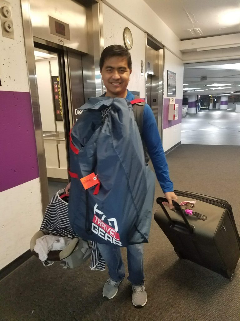 Man carrying a car seat in a travel bag