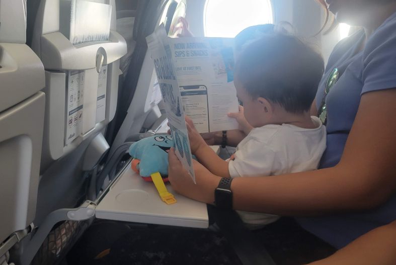 Baby looking at airplane magazine on the plane