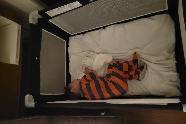Baby sleeping in a crib in a hotel