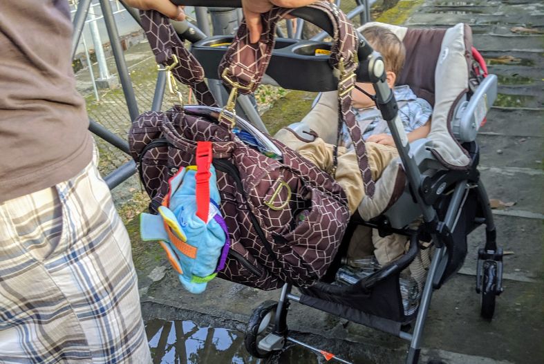 A diaper bag attached to a stroller during travel