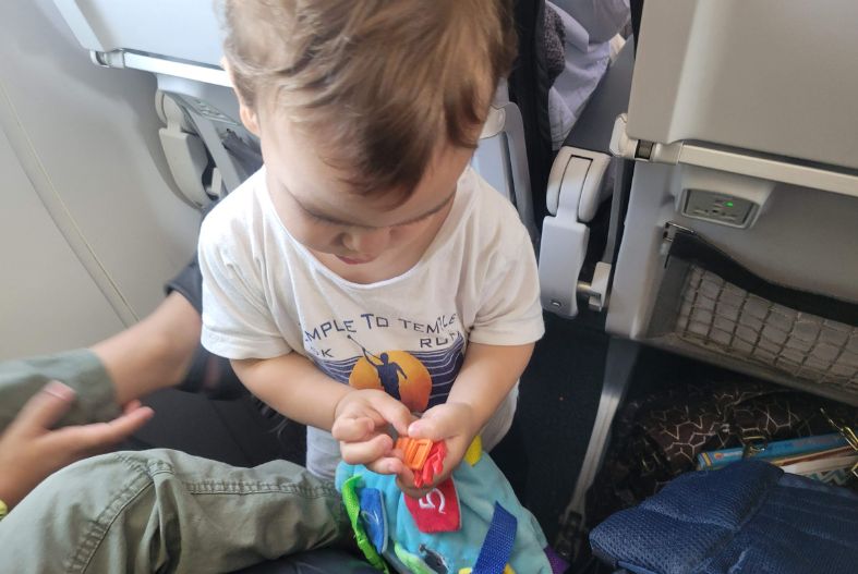 Toddler on plane with buckle toy