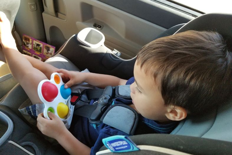 Toddler playing with fidget popper in car