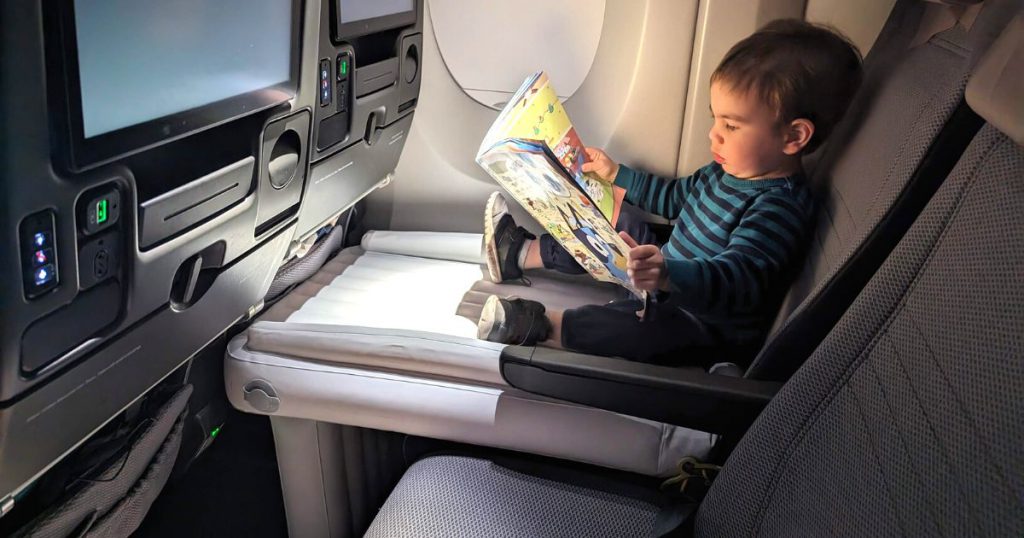 Child sitting on a Flyaway kids bed on a plane