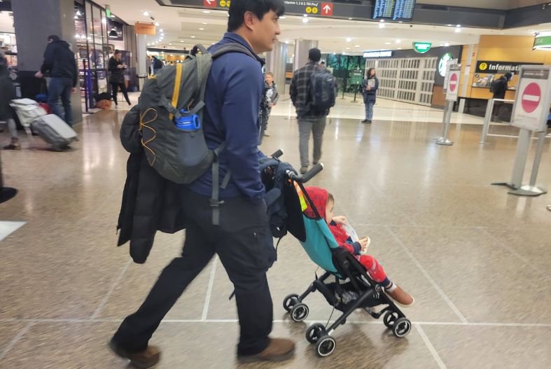 Man pushing a child in a gb Pockit stroller through the airport