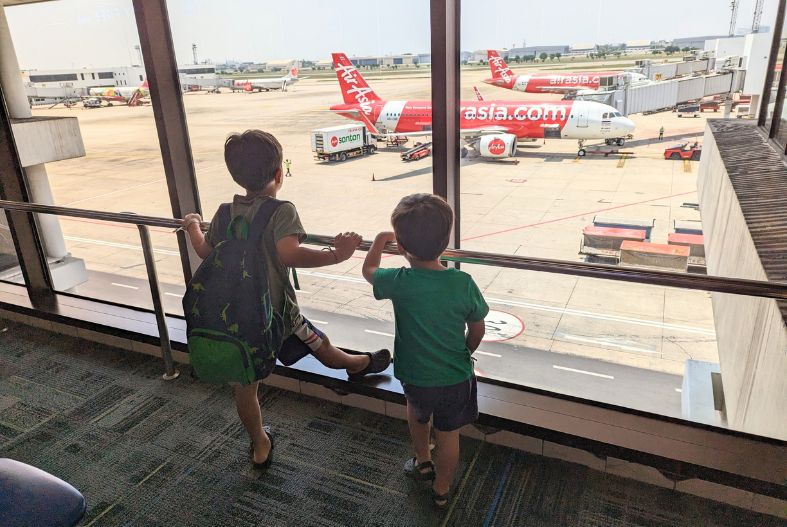 Kids looking at an airplane from inside an airport