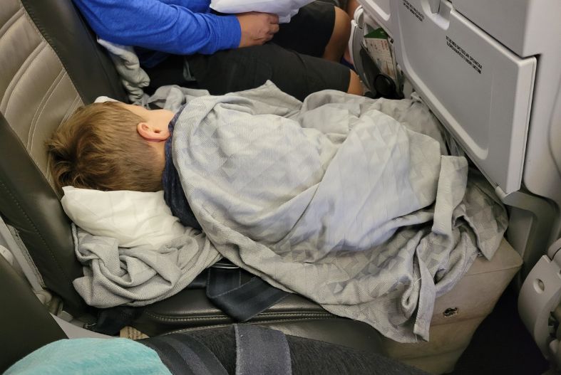 Child sleeping on a plane using an inflatable footrest