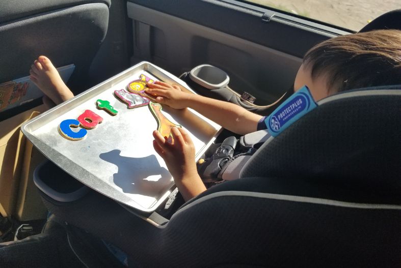 Child playing with magnets on a cookie sheet on a road trip